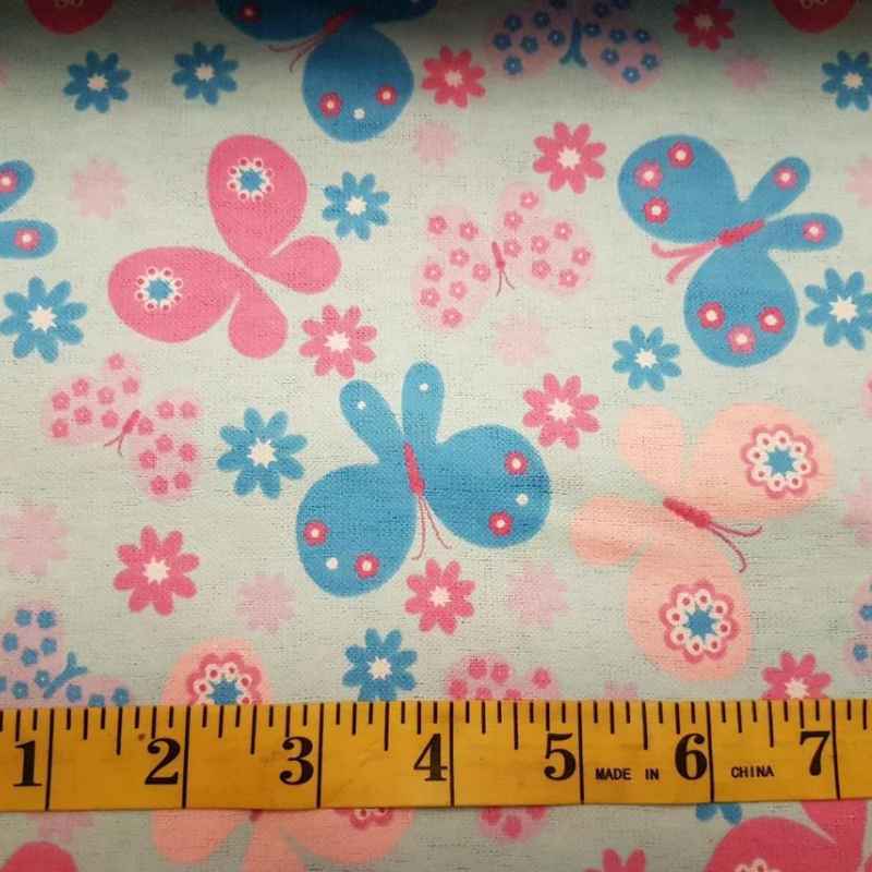 Pink, peach, and blue butterfly cotton flannel fabric with floral accents, quilting weight, perfect for blankets, quilts, and kids' sewing projects.