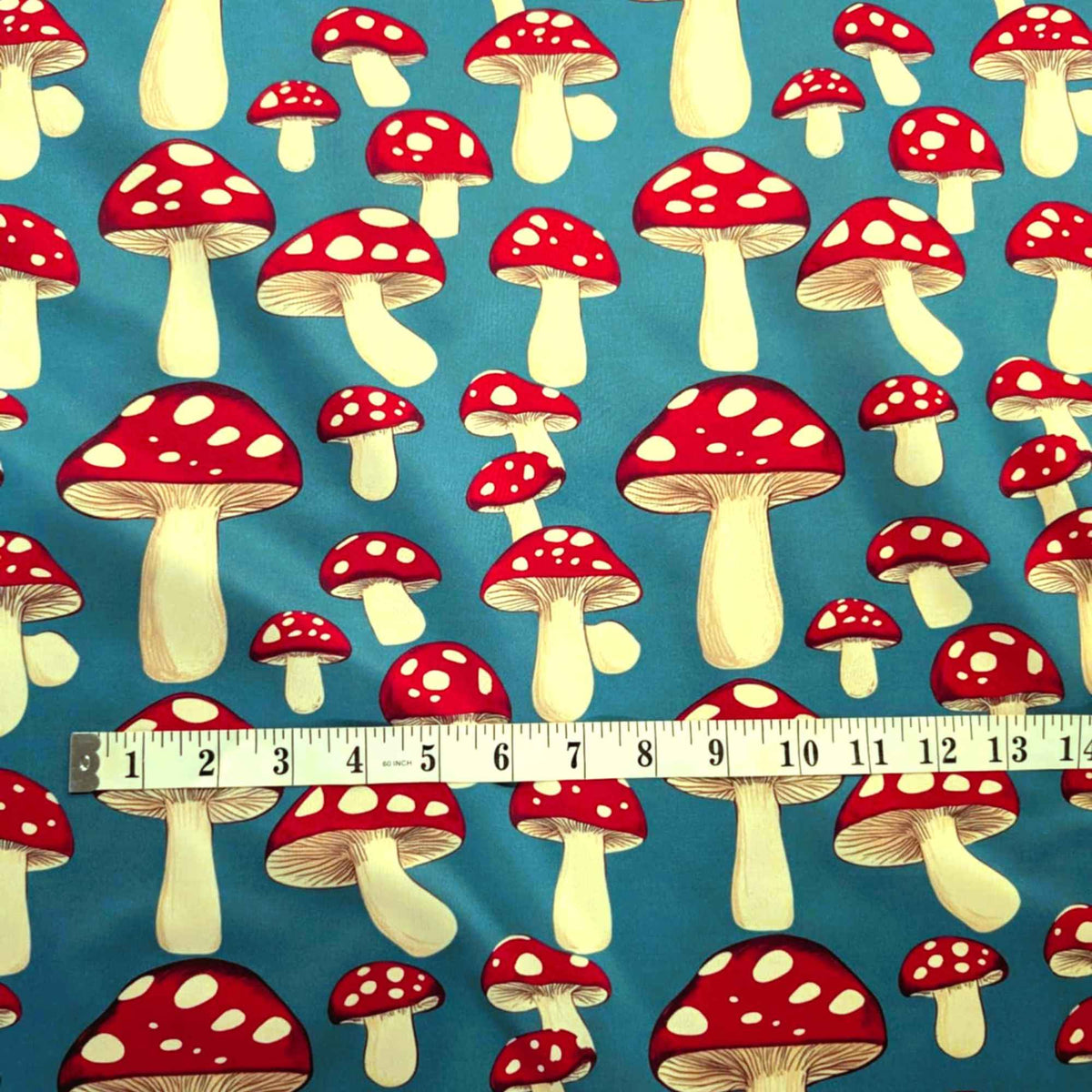 Red toadstool mushroom print food safe waterproof PUL fabric on blue background with white spotted mushrooms.