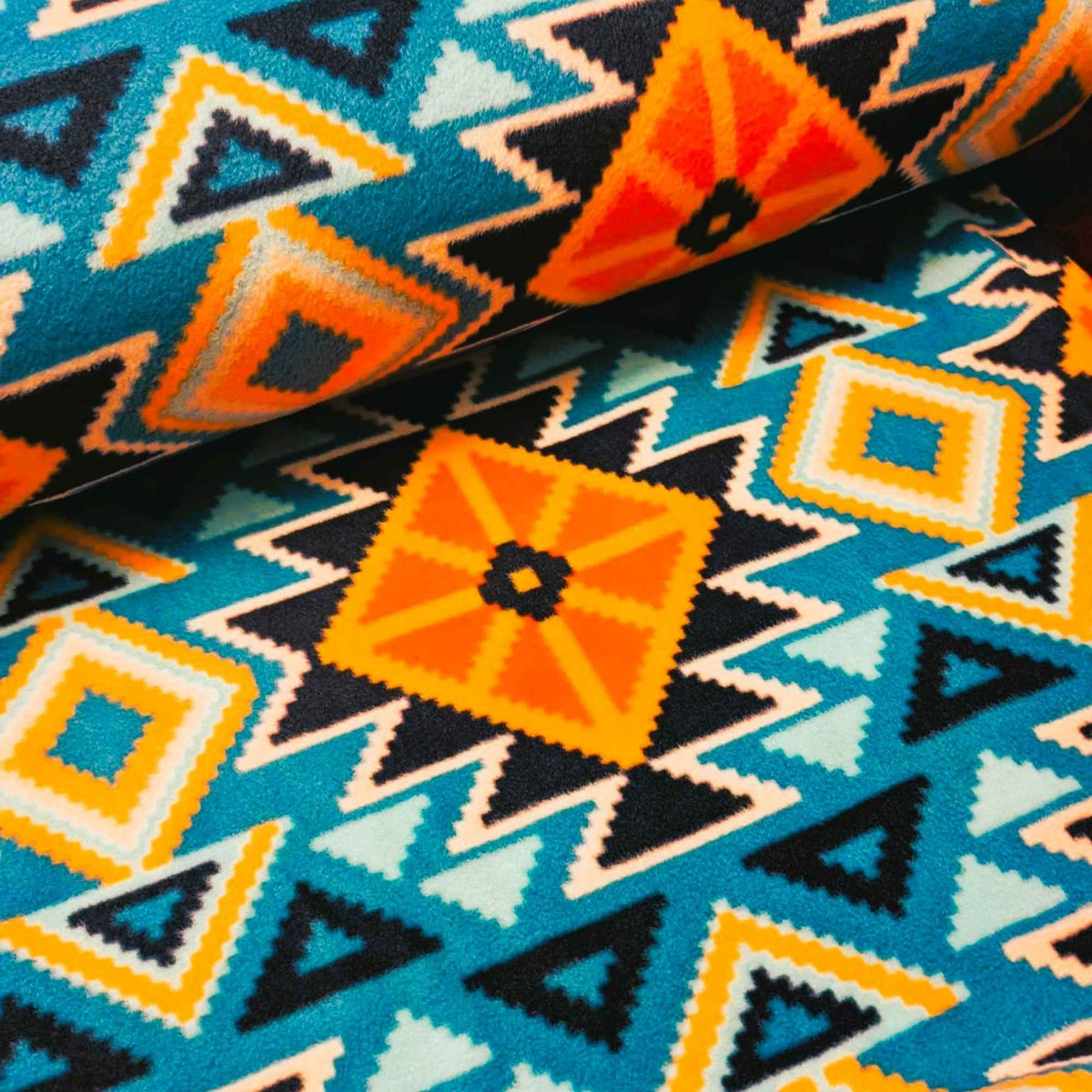 To the Mountains fleece fabric by Camelot, with teal and orange diamonds, navy triangles and cream zigzag detail.