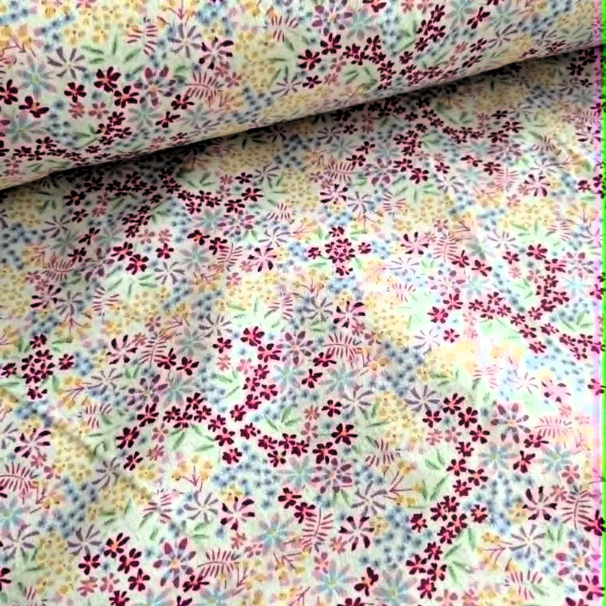 Double brushed flannel fabric featuring pastel wildflowers and delicate floral sprigs in pink, lavender, blue, yellow, and green on a white background.