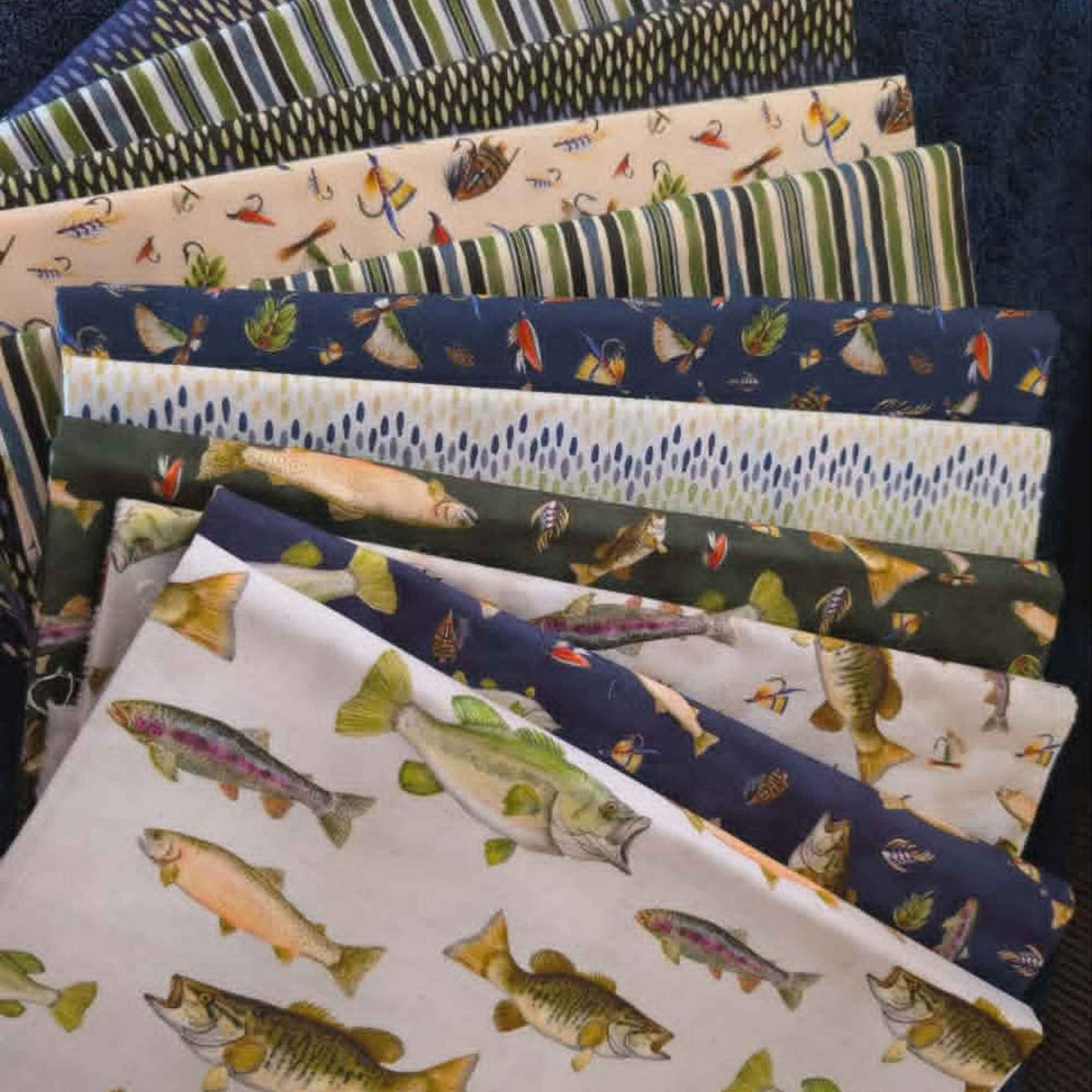 Fishful Thinking fabric bundle by Camelot Fabrics and Brett Blumenthal featuring 11 coordinating quilting cotton prints with fish, fishing lures, tackle, stripes, and rustic outdoor patterns in navy blue, green, cream, and natural tones