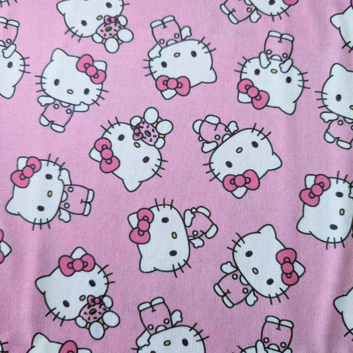 Officially licensed Hello Kitty cotton fabric by Springs Creative featuring an all-over toss of Hello Kitty holding a teddy bear on a pink background.