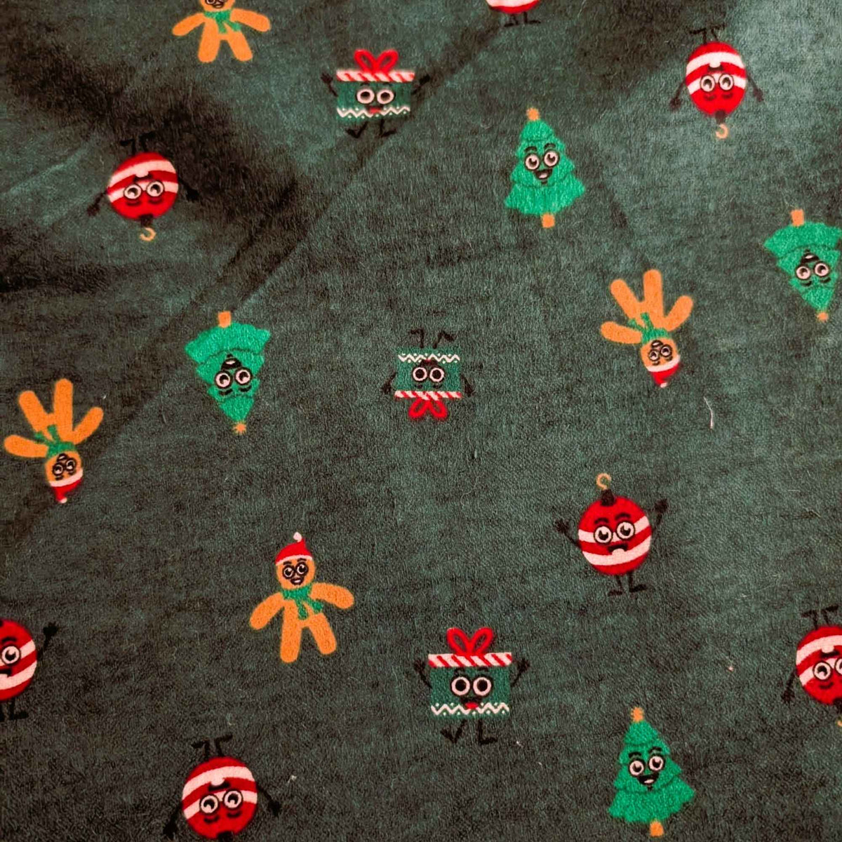 Dark green cotton flannel with smiling Christmas trees, gingerbread figures, red and white ornaments, and gift boxes.