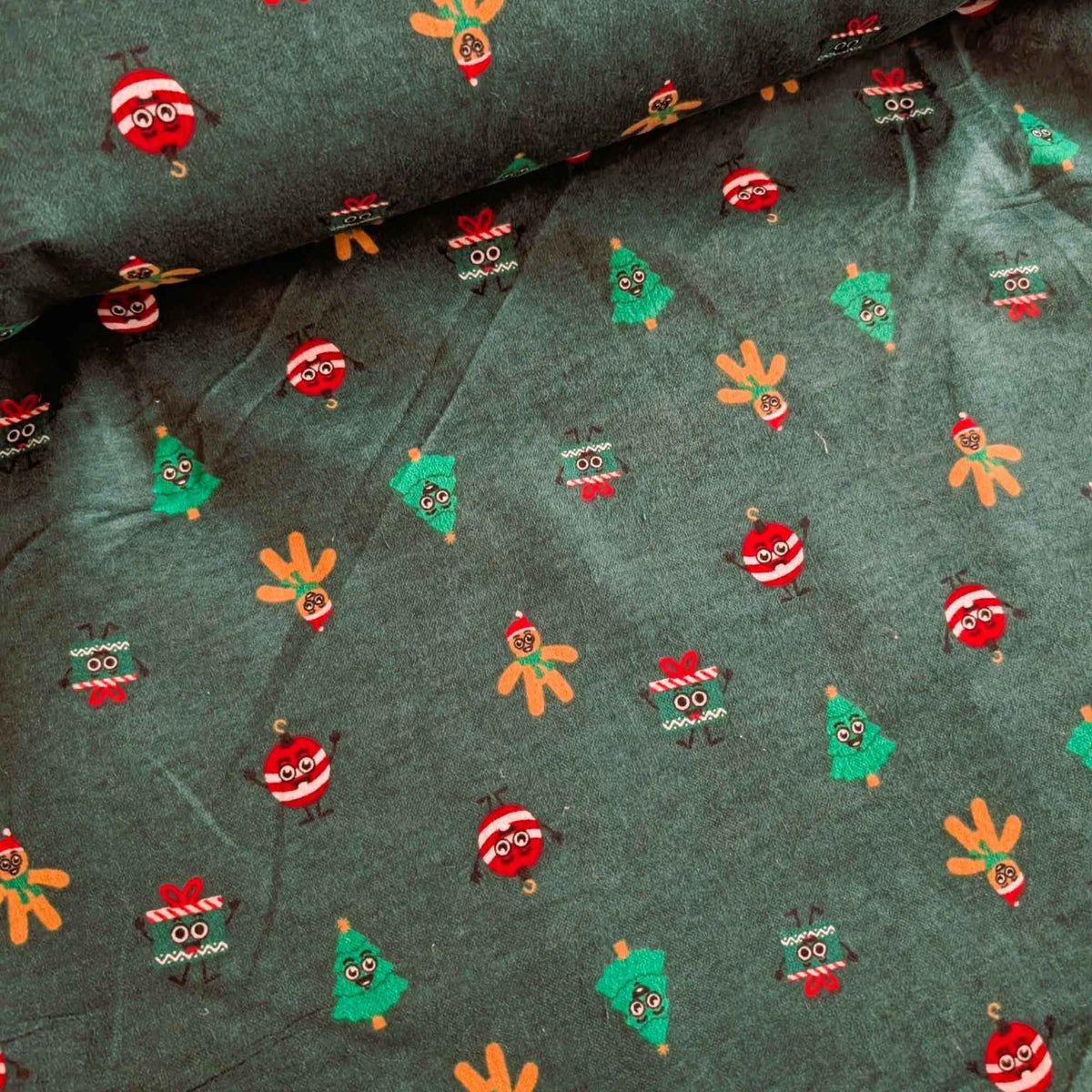 Dark green cotton flannel with smiling Christmas trees, gingerbread figures, red and white ornaments, and gift boxes.