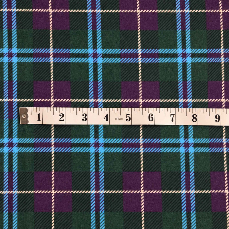 Teal green and purple tartan plaid cotton flannel fabric with bright blue crossing bands, thin cream lines and black accents.