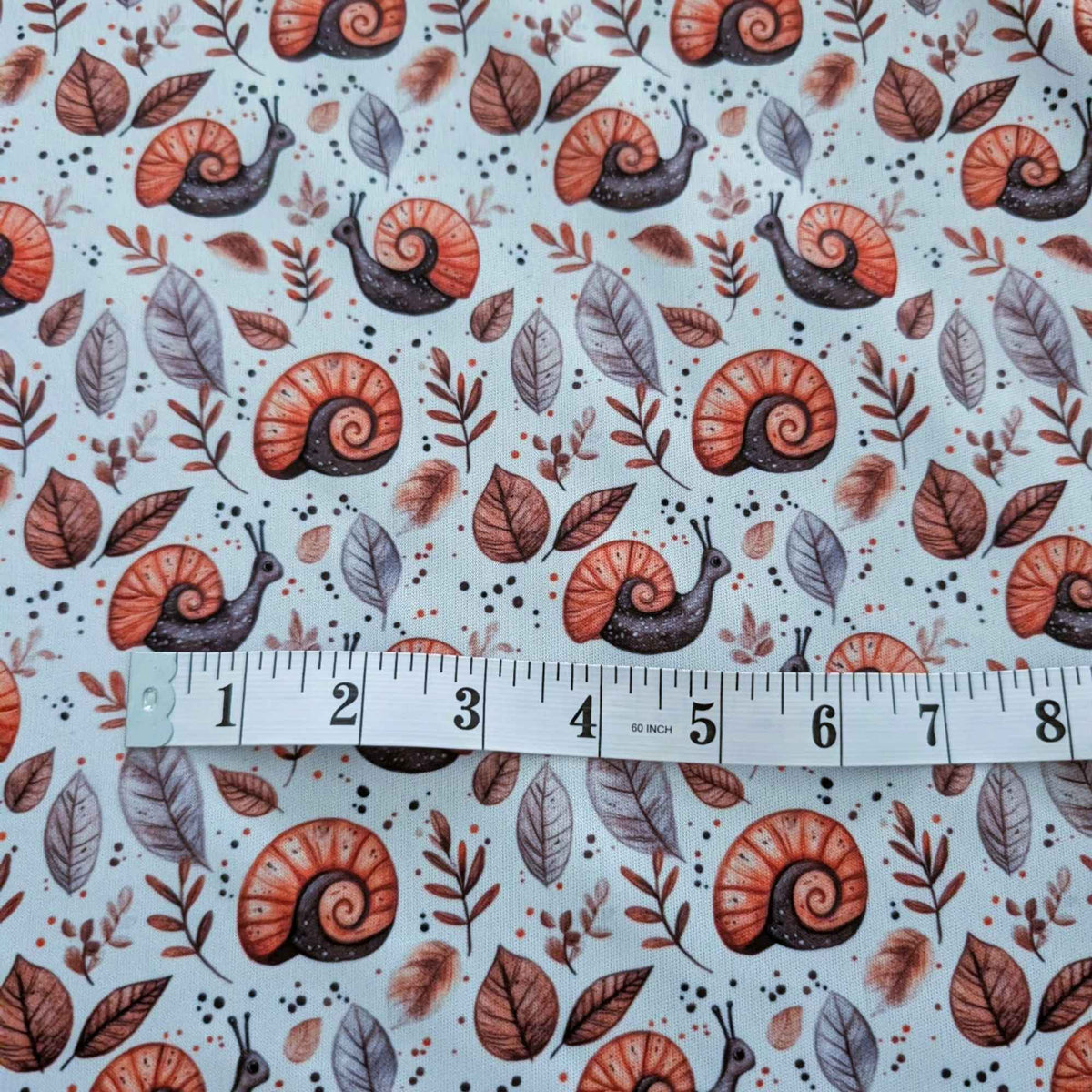 Woodland Snails and Autumn Leaves exclusive waterproof PUL fabric with orange-shelled snails and brown leaves on cream