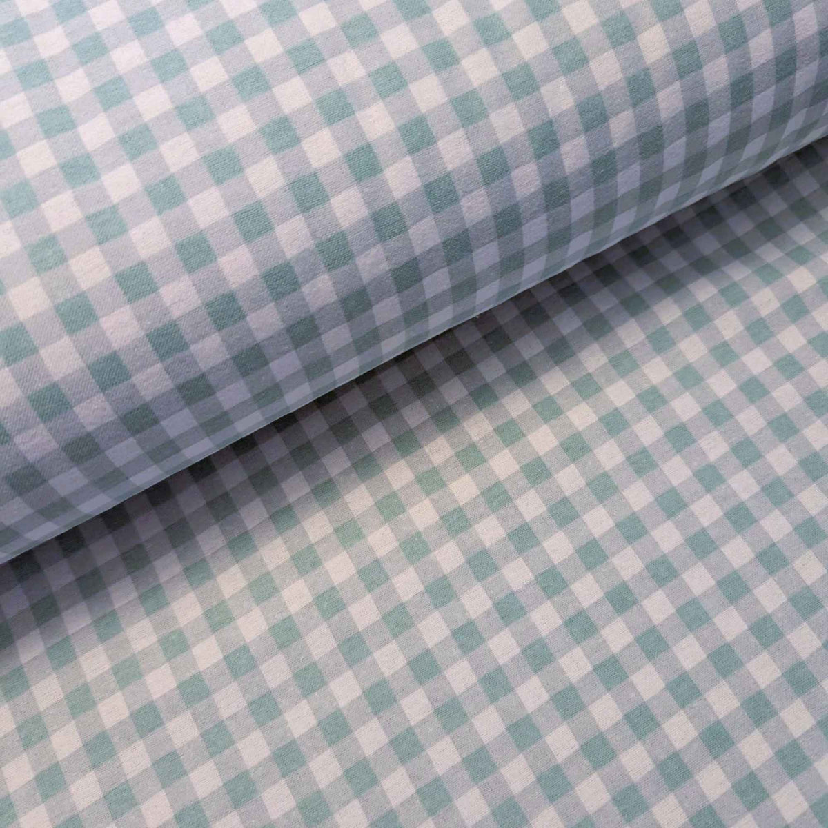 A close-up of a light blue and white gingham patterned fabric, shown with one corner rolled back to display the texture and pattern repeat.