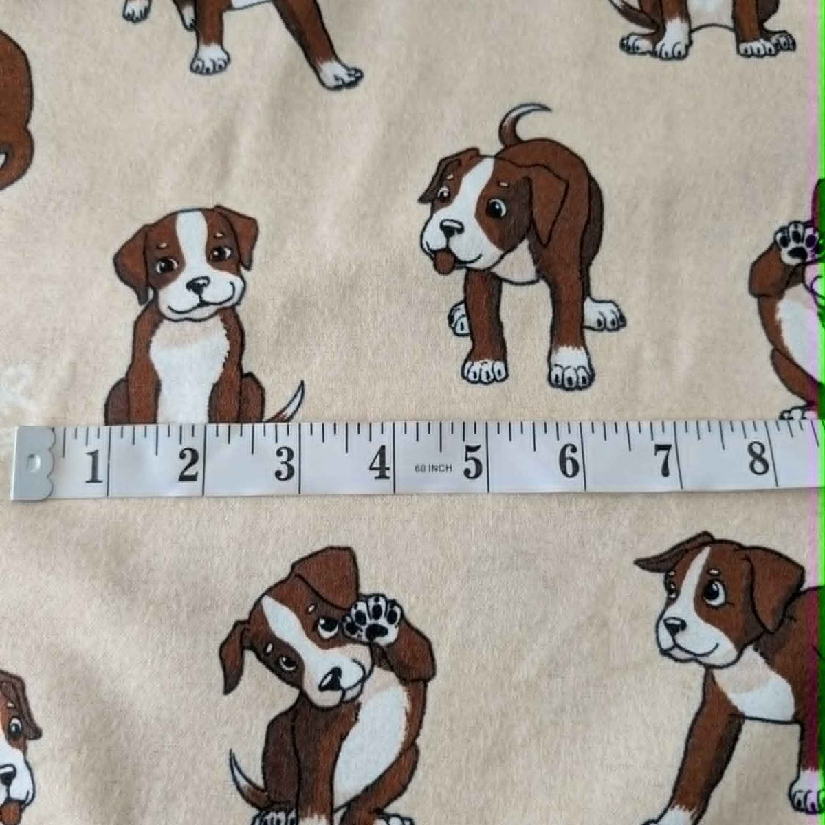 Double brushed flannel fabric featuring playful brown and white puppies in various poses on a cream background.