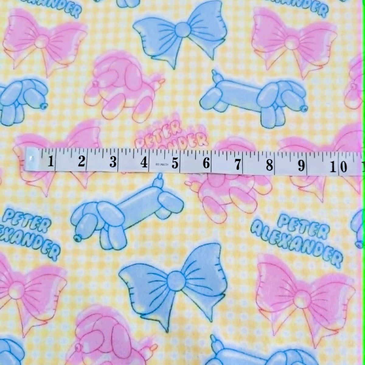Double brushed flannel fabric featuring pastel balloon dogs, decorative bows, and a yellow gingham background in pink and blue tones.