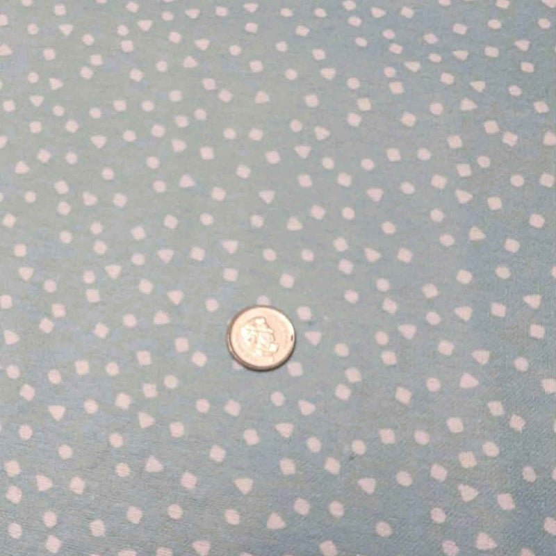 A close-up of a light blue fabric with a repeating pattern of small white hearts, with a small coin placed in the center for scale.