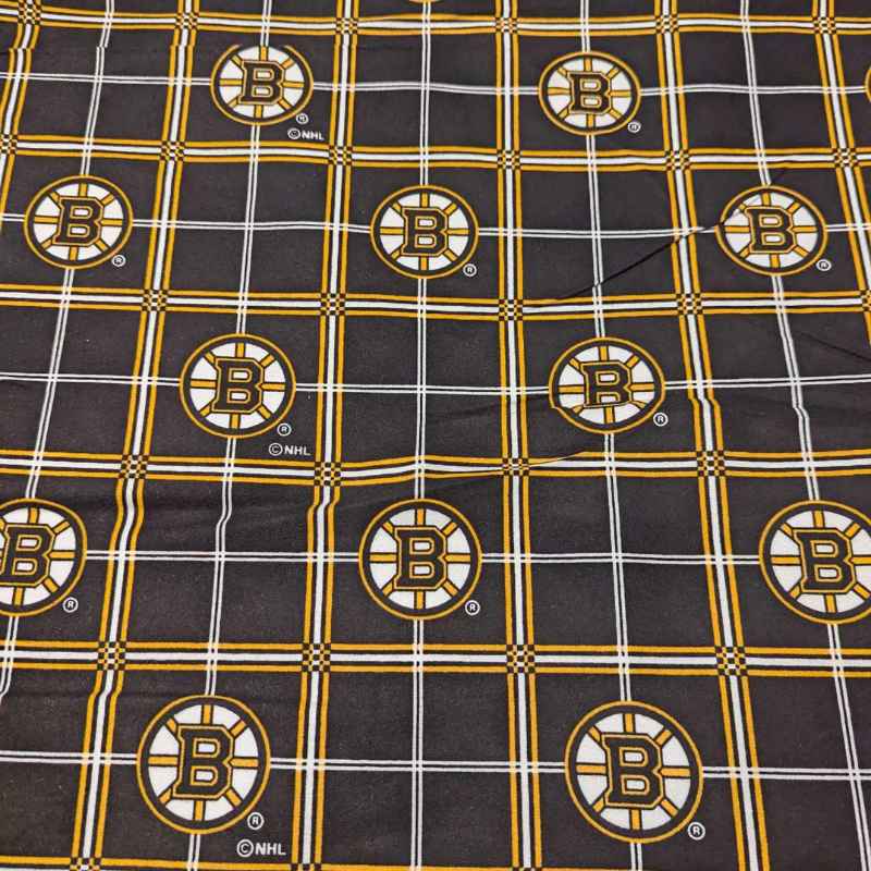 Boston Bruins plaid flannel cotton fabric with black, gold, and white tartan design and repeating NHL Bruins logos.