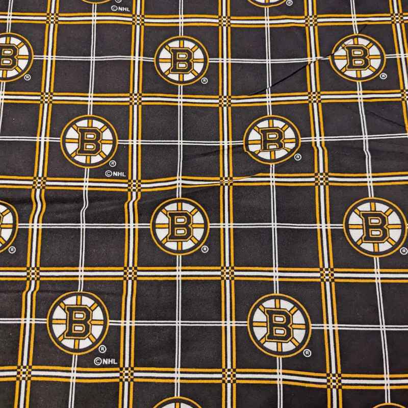 Boston Bruins plaid flannel cotton fabric with black, gold, and white tartan design and repeating NHL Bruins logos.