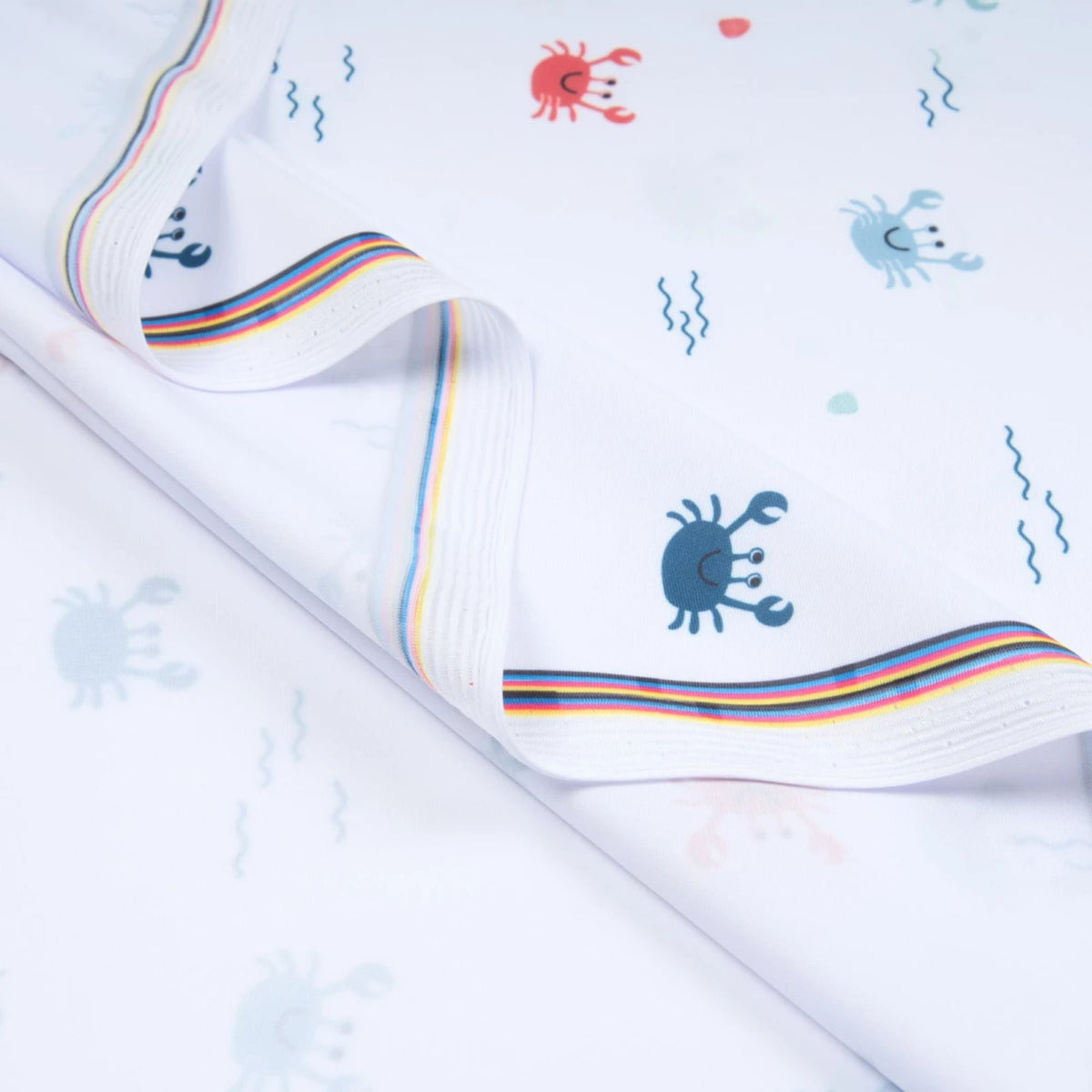 White swim fabric with playful red, blue, and mint crabs and beach motifs – Oeko-Tex certified stretch knit for kids' swimwear and ocean-themed projects