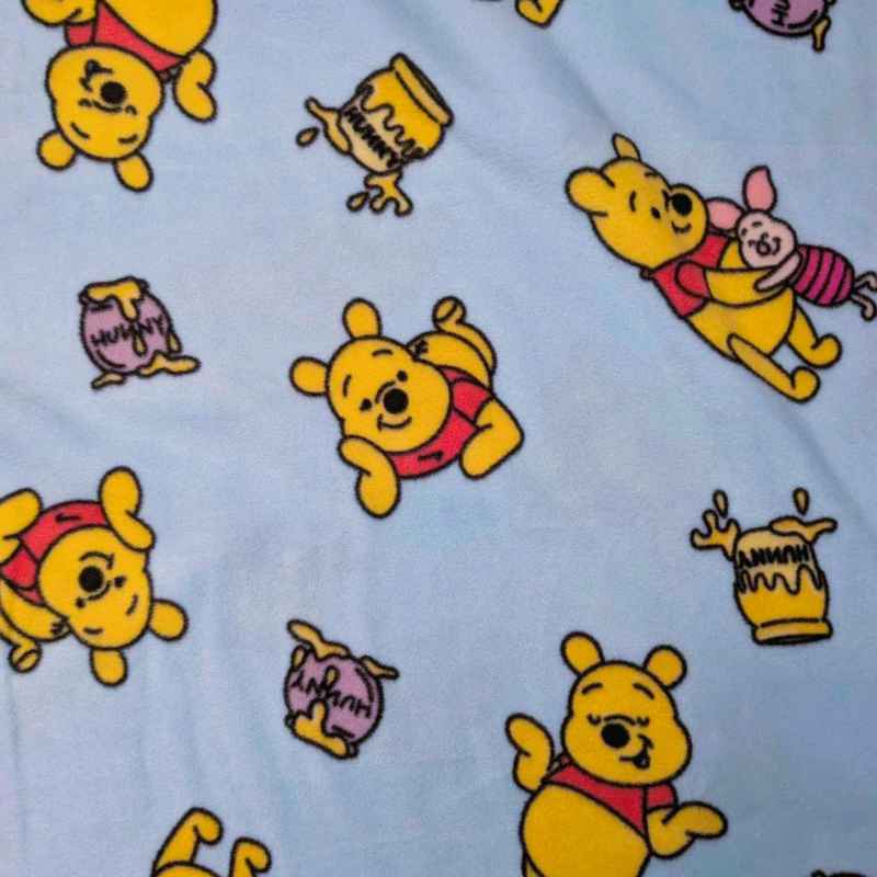 Winnie the Pooh anti-pill fleece on light blue with honey jars. Soft, cozy fabric for blankets, scarves, and crafts.
