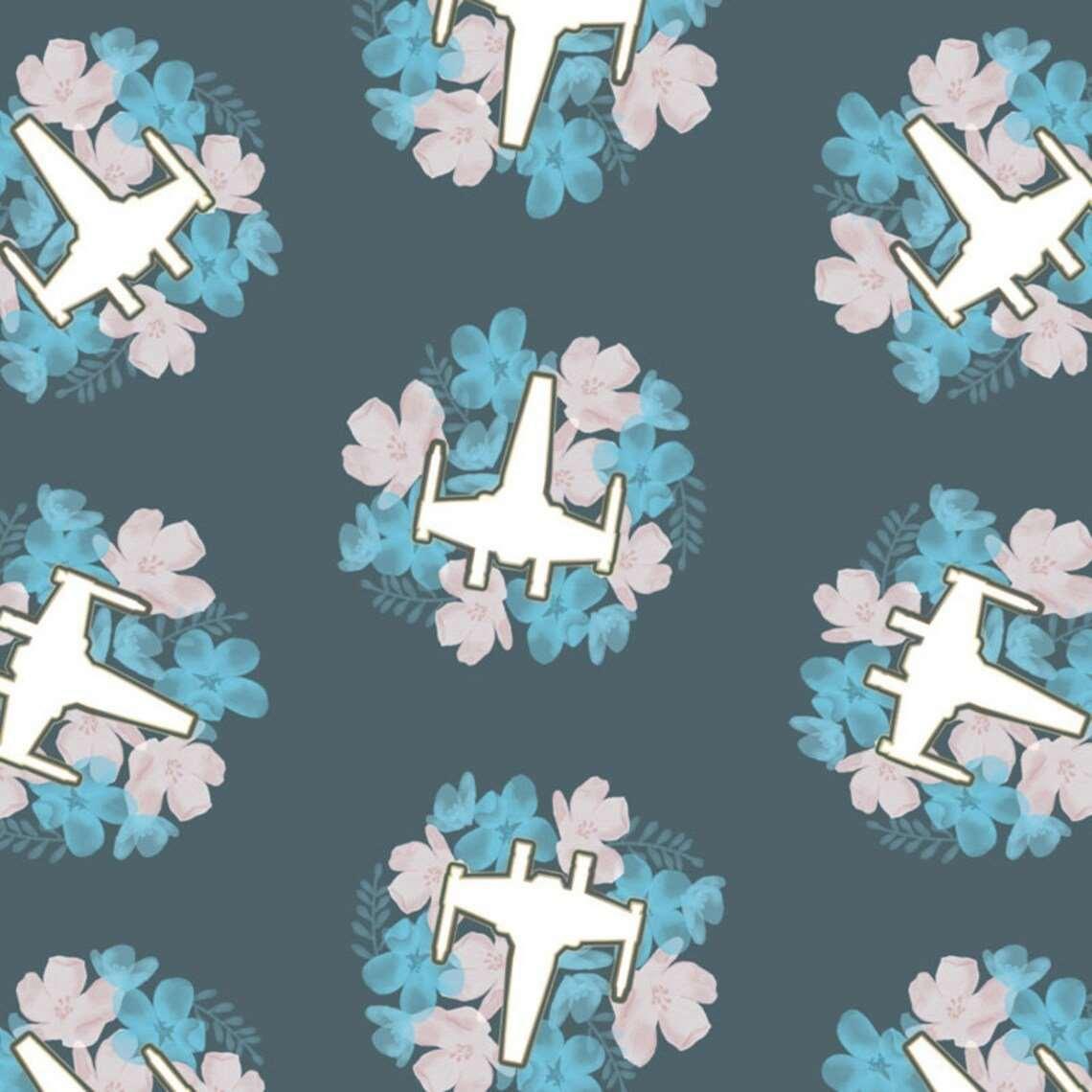 Camelot Fabrics Star Wars print with cream starfighters inside pink and blue floral wreaths on a slate-grey background